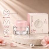 Kulio Moisturizing Face Cream in a clear glass jar with a pink lid and matching retail packaging, displayed on a marble pedestal with moisturizing, protection, and softening benefits.